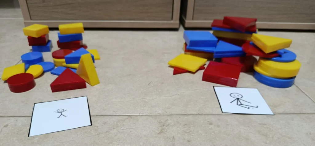 Juego de ordenación de bloques lógicos en el que organizamos las piezas en función de su tamaño (grande y pequeño) separándolas con cartulinas indicadoras de tamaño